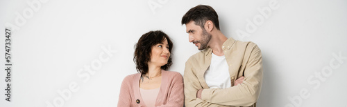 Bearded man crossing arms and looking at wife on white background, banner.