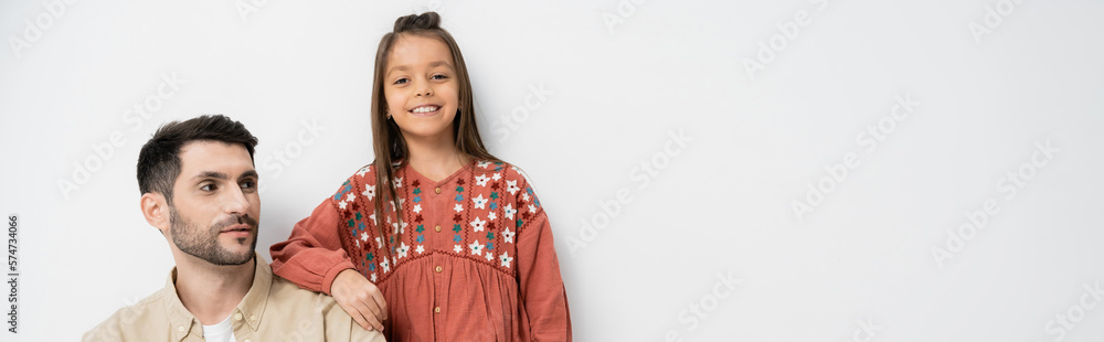 Smiling girl standing near father on white background, banner. Smiling girl standing near father on white background, banner.