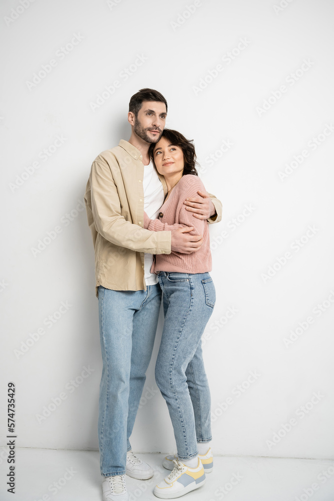 Full length of couple hugging and looking away on white background. Full length of couple hugging and looking away on white background.