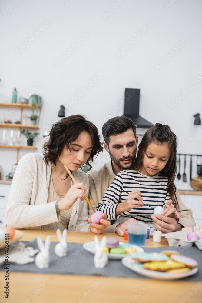 Family with daughter painting eggs during Easer at home. Family with daughter painting eggs during Easer at home.