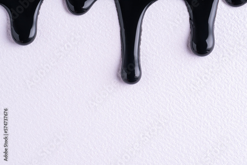 Fotografia Black liquid drops of paint color flow down on white canvas