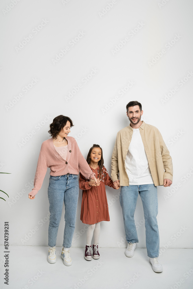Smiling parents and kid holding hands on white background. Smiling parents and kid holding hands on white background.