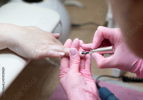 a master does a manicure to a client in a beauty salon and covers her nails
