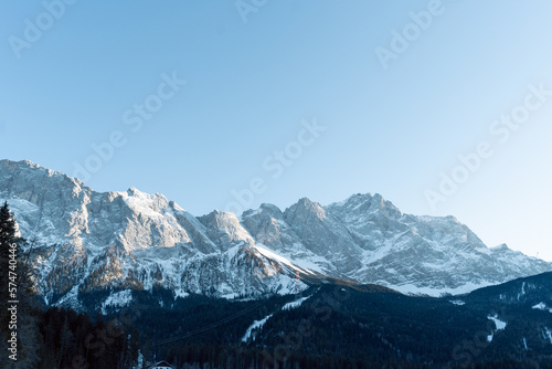 the beautiful eibsee in the foreground at the valley station of the zugspitzbahn in the south of germany where the mountains are illuminated by the sun and are covered with snow