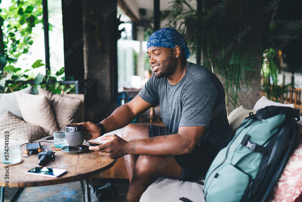 African American traveler drinking coffee and browsing smartphone in cafe African American traveler drinking coffee and browsing smartphone in cafe