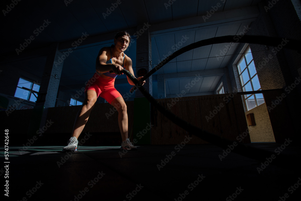 Athletic woman doing double wave exercise with ropes in crossfit gym. Athletic woman doing double wave exercise with ropes in crossfit gym.