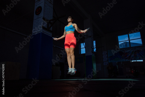 Athletic woman performs jumping rope in crossfit gym. © kanashkin