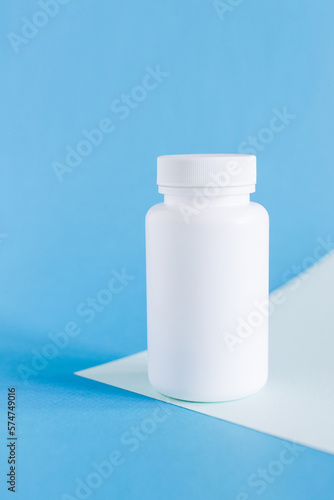 white medicine or vitamin bottle mockup on blue background, pill bottles without label design, copy space