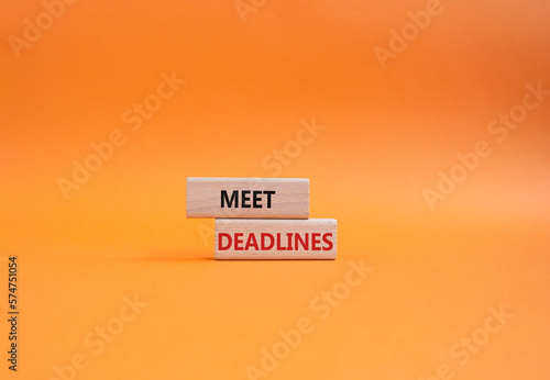 Meet Deadlines symbol. Concept word Meet Deadlines on wooden blocks. Beautiful orange background. Business and Meet Deadlines concept. Copy space