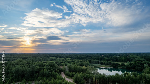 Aerial panoramic landscape over a winding forest road in Belgium  during sunset  drone shot. High quality photo