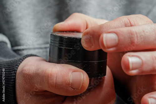 Close up of two hands holding a grinder. Weed, cannabis, marijuana grinder for smoking joints and blunts