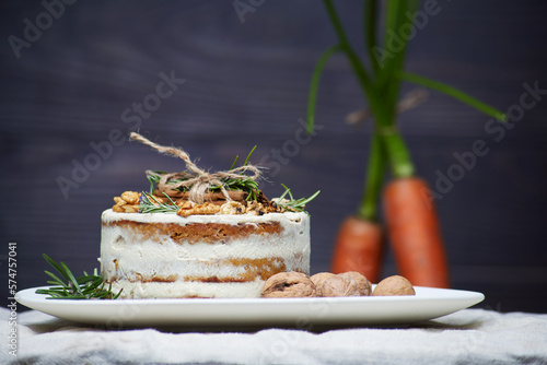 Traditional carrot cake with walnut with art stylysh carrots on the behind photo