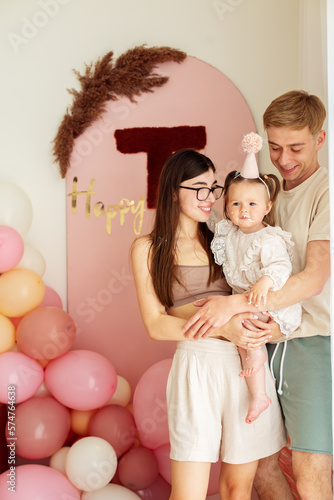 One year old little girl with daddy and mammy solemnize birthday. Happy laughter. photo