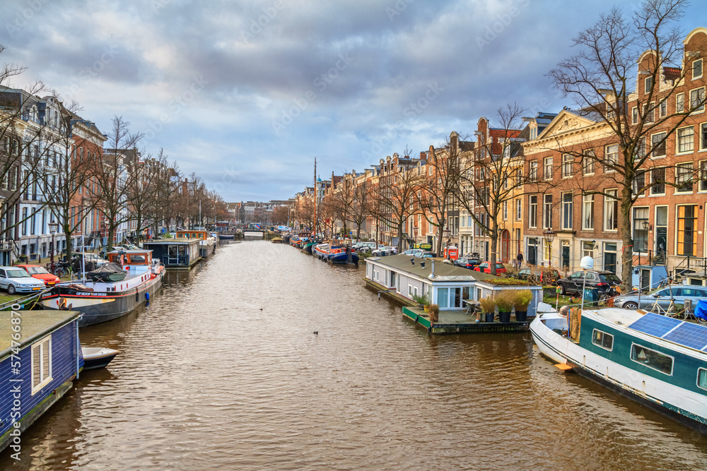 Cityscape on a sunny winter day - view of the water canal with houseboats in the historic center of Amsterdam, the Netherlands