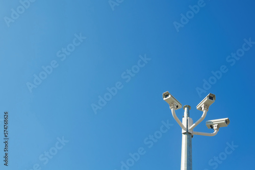 Three CCTV surveillance cameras against blue sky