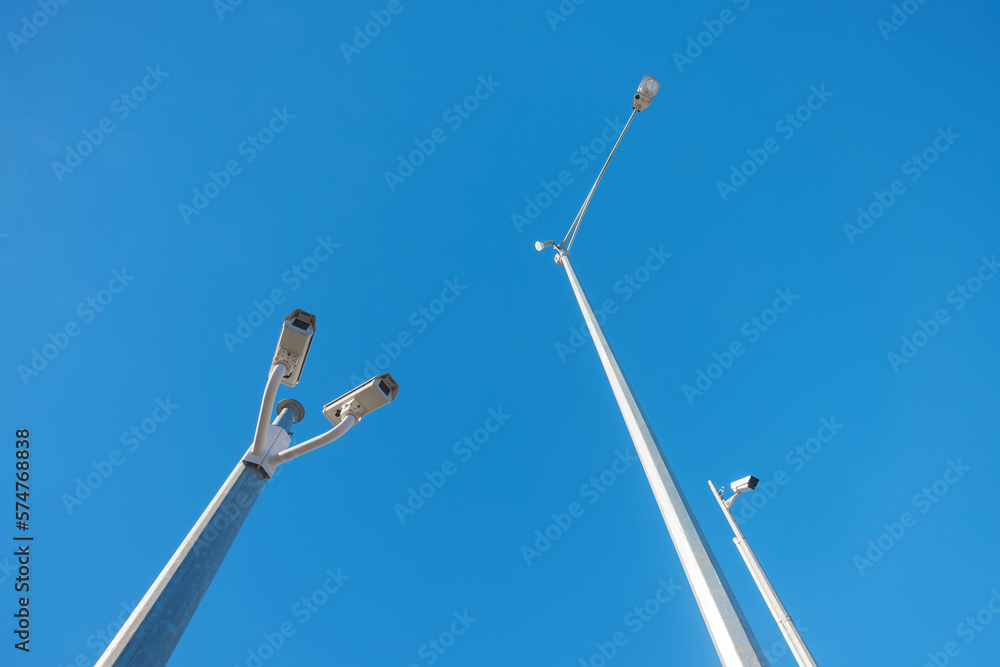 Closed circuit television cameras and streetlight against blue sky Closed circuit television cameras and streetlight against blue sky