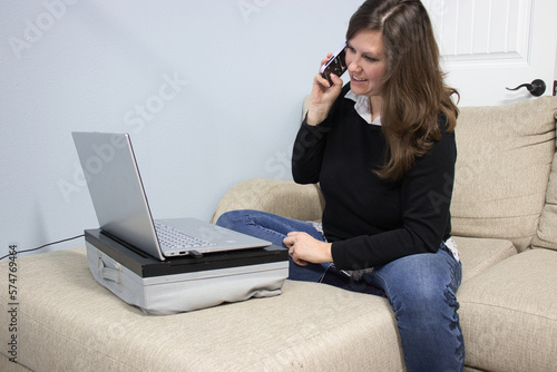 A woman with laptop and phone working from home on the couch