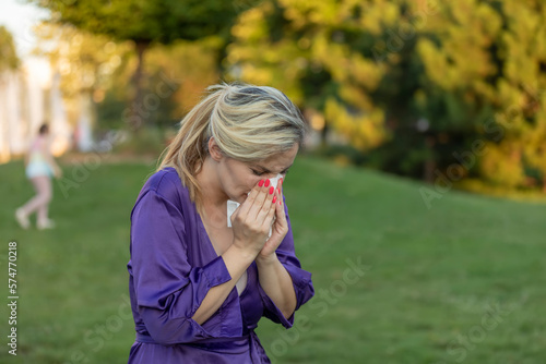 Cold and flu. Young attractive woman, caught a cold, wipes her nose with a napkin.