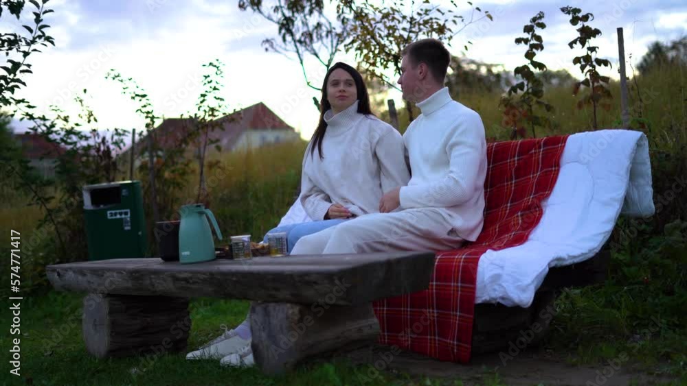 Couple relaxing on bench in nature, talking each other, kissing, talking, enjoying Couple relaxing on bench in nature, talking each other, kissing, talking, enjoying