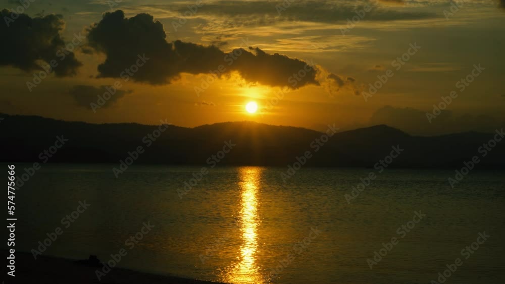A cloudy sky during sunset with a yellow sun reflecting in the sea A cloudy sky during sunset with a yellow sun reflecting in the sea