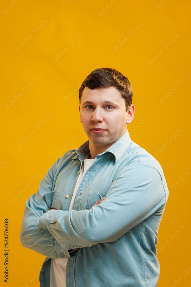Portrait of handsome european man in shirt looking at camera standing on yellow studio background Portrait of handsome european man in shirt looking at camera standing on yellow studio background