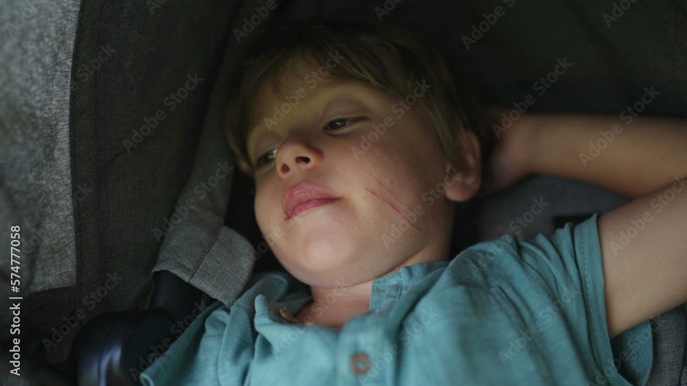 One small boy sitting inside stroller waking up from nap One small boy sitting inside stroller waking up from nap