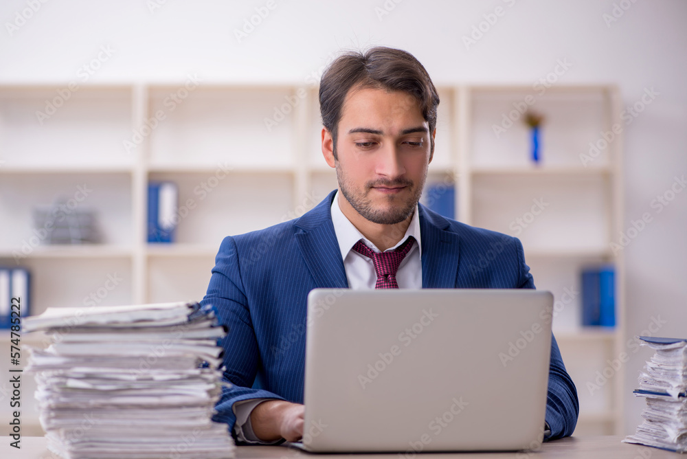 Young male employee and too much work in the office Young male employee and too much work in the office