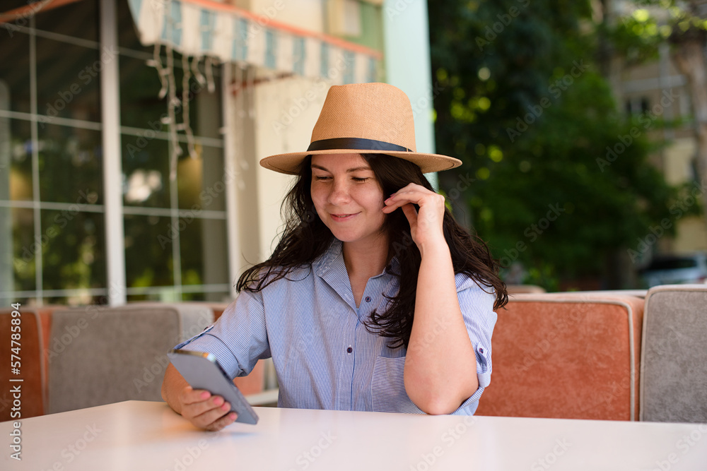 Stylish woman in hat with smartphone outside,making video call and smile.