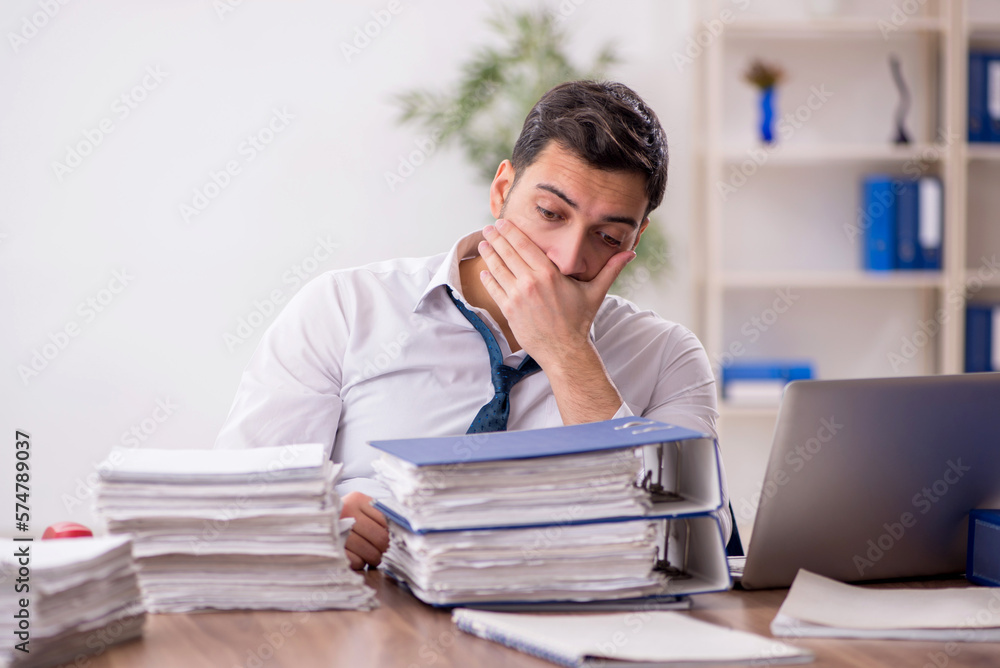 Young male employee and too much work in the office Young male employee and too much work in the office