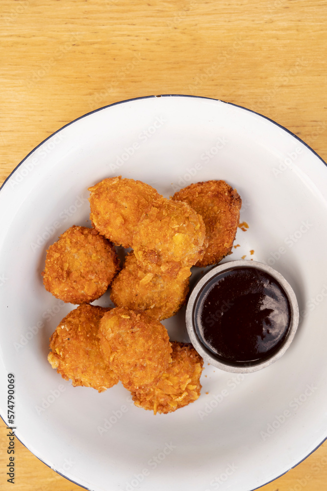 Closeup view of fried chicken balls with a spicy sauce in a white bowl. Closeup view of fried chicken balls with a spicy sauce in a white bowl.
