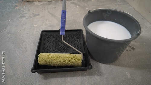 Stir the white primer to the desired consistency. Water is poured into the primer. The primer is diluted with water to the desired consistency. We breed a white primer for construction work. photo