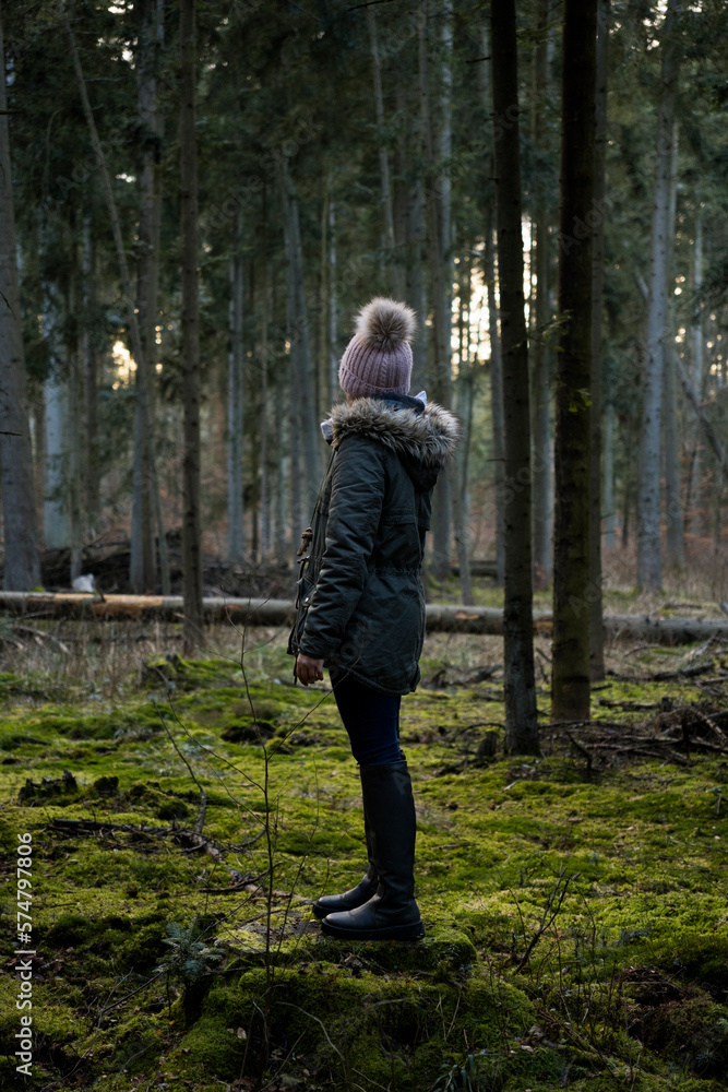 Girl in the middle of a fir forest standing on a mossy stump
