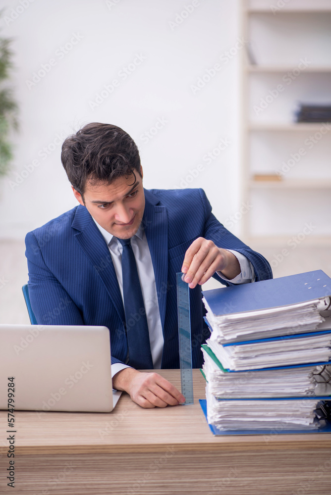 Young male employee and too much work in the office Young male employee and too much work in the office