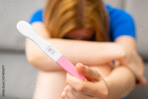 Disappointed woman holding a positive pregnancy test. Unexpected results.  © vladim_ka