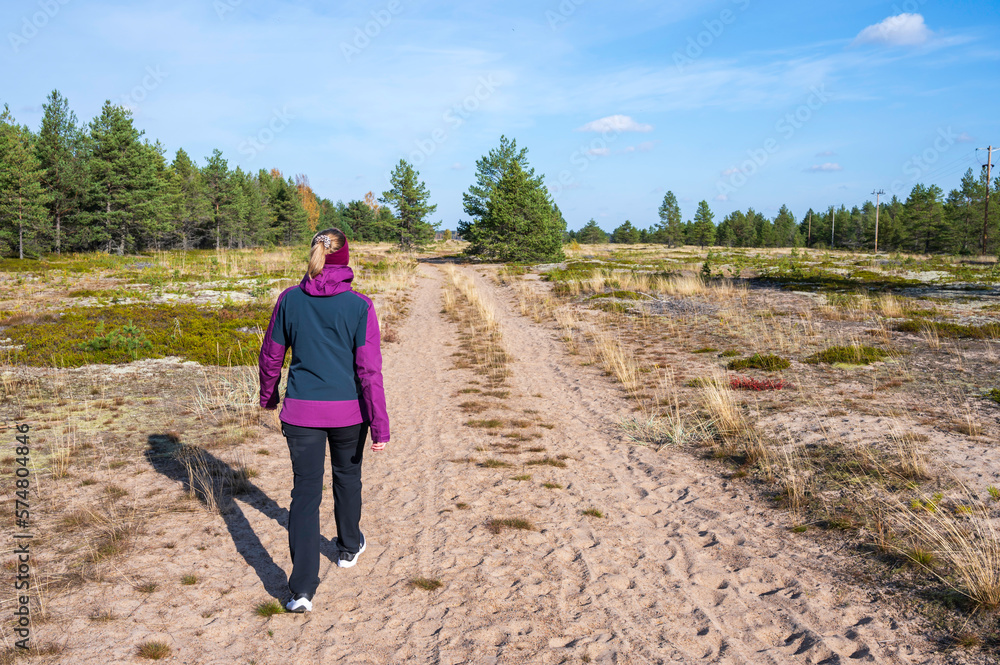 Woman walking on a sandy trail. Storsand, Monäs. Nykarleby/Uusikaarlepyy, Finland