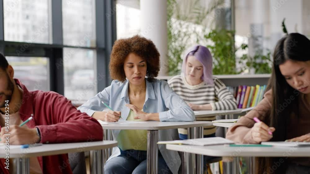 Slow motion of a female student writing off a test from a classmate during a school exam Slow motion of a female student writing off a test from a classmate during a school exam