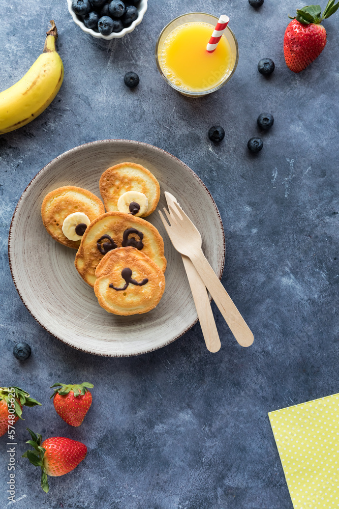 Fototapeta premium Homemade keto diet pancakes in the shape of a bear served with fruit and juice.