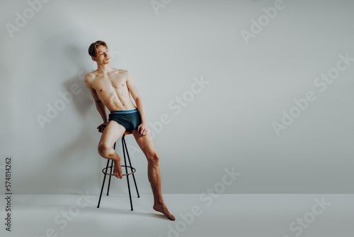 skinny and scrawny boy is rawboned and underweight but show proud and confident his body positivity and slim shape while sit on barstool and have self-esteem and self love for his anatomy