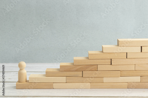Foto wooden figurine of a man stands on a staircase made of blocks on the first step