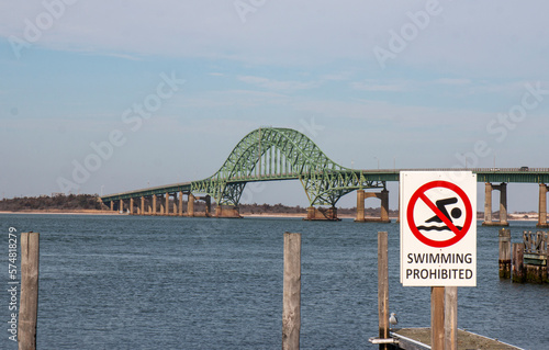 Swimming prohibited sign with the Robert Moses Bridge in the background over the inlet photo