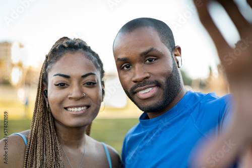 Healthy lifestyle concept. Dark-skinned couple doing outdoor sports together, man and woman take a photo with their mobile, The woman and the man come out smiling looking at the camera.
