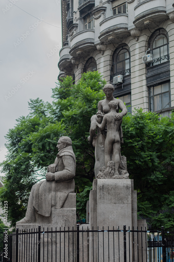 Statues in the city, on a cloudy day, with trees behind