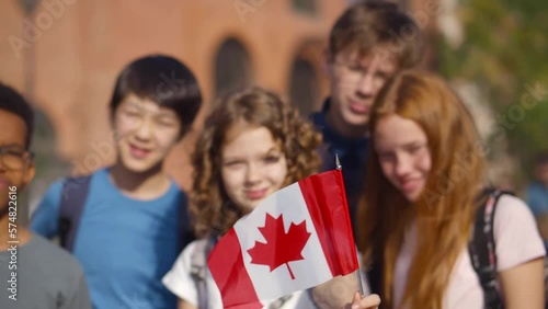 Portrait of group of diverse school kids with Canadian flag outside school. Realtime