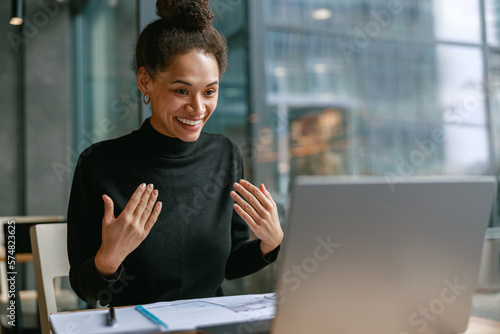 Smiling woman freelance talking with client via video call and discuss project sitting in cafe