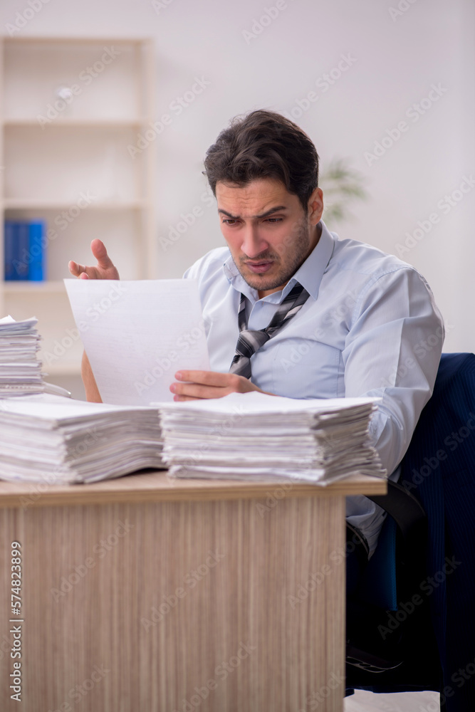 Young male employee and too much work in the office Young male employee and too much work in the office