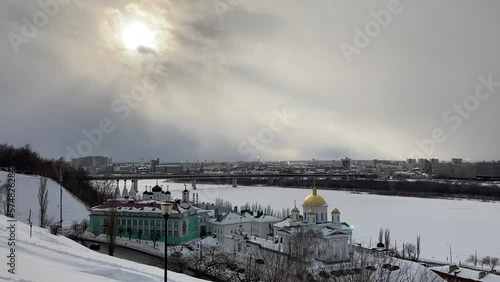 View from Fedorovsky Embankment in Nizhny Novgorod at the Annunciation Monastery in the foreground and the icy Oka river, the Metro Bridge and the Lower City in the background under a dim winter sun photo