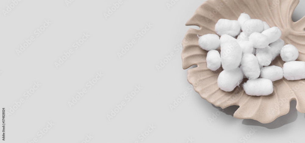 Plate with soft cotton balls on light background with space for text Plate with soft cotton balls on light background with space for text