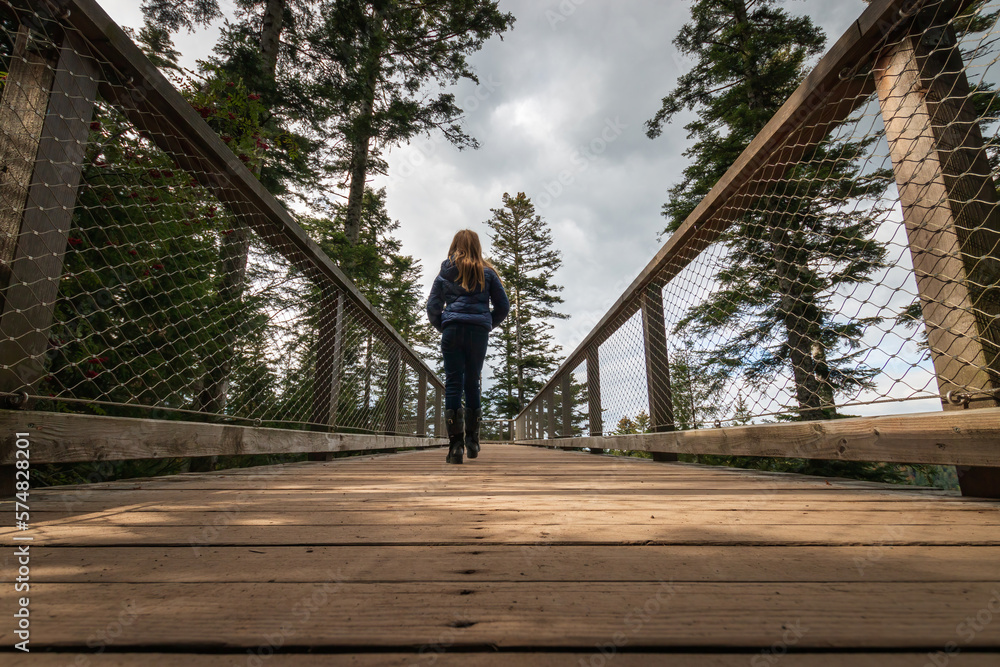 Girl walking on trail of the treetop path called Baumwipfelpfad Schwarzwald, Germany