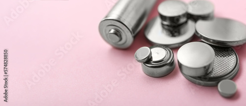 Different batteries on pink background, closeup. Banner for design photo