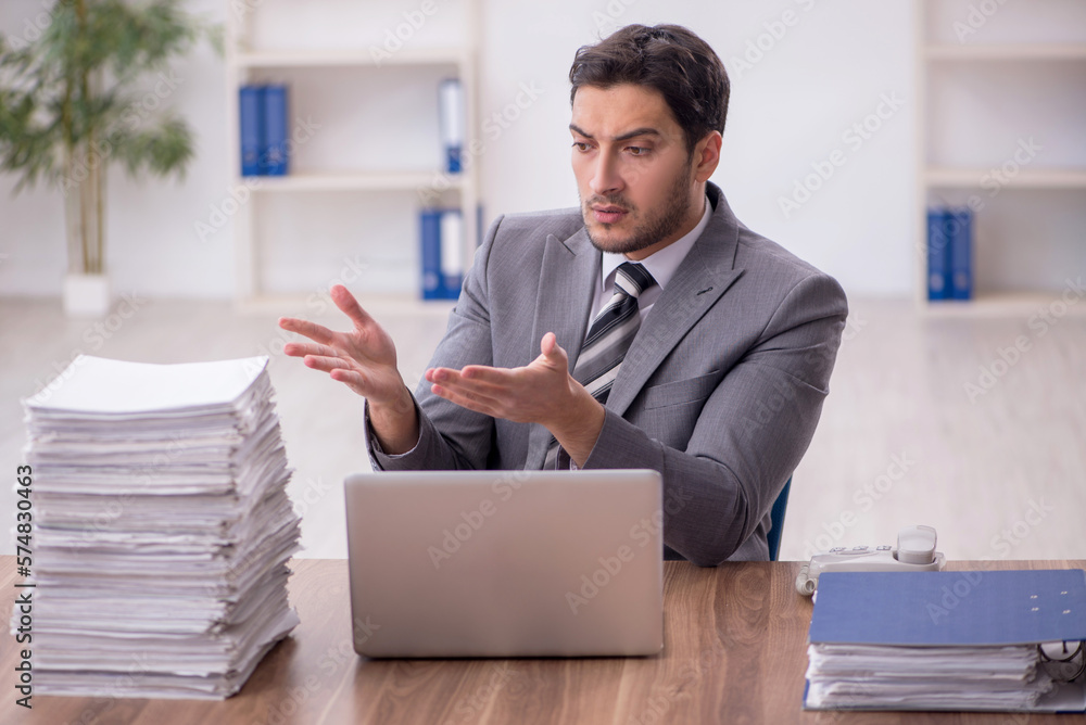 Naklejka premium Young male employee and too much work in the office